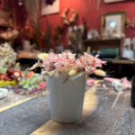 Enfant en train de décorer une tasse en fleurs séchées lors d'un atelier créatif